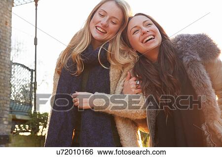 Two female friends outdoors, walking arm in arm, laughing View Large Photo Image Stock Photograph - Two female friends outdoors, walking arm in arm, laughing. Fotosearch