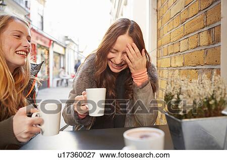 Two female friends, sitting outdoors, drinking coffee, laughing View Large Photo Image Stock Photo - Two female friends, sitting outdoors, drinking coffee, laughing. Fotosearch