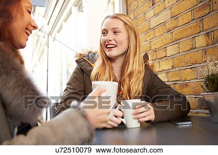 Two female friends, sitting outdoors, drinking coffee, laughing View Large Photo Image Stock Photo - Two female friends, sitting outdoors, drinking coffee, laughing. Fotosearch