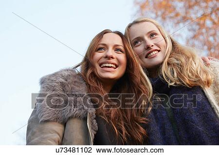 Stock Image - Two female friends, walking outdoors, smiling. Fotosearch