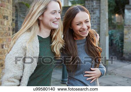Two female friends walking outdoors, laughing View Large Photo Image Stock Image - Two female friends walking outdoors, laughing. Fotosearch