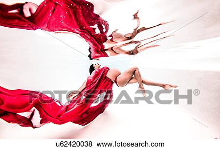 Stock Photo - Underwater view of poised young pregnant woman with flowing red textile. Fotosearch