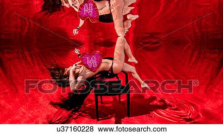 Stock Photo - Underwater view of woman poised over a chair holding a love heart. Fotosearch