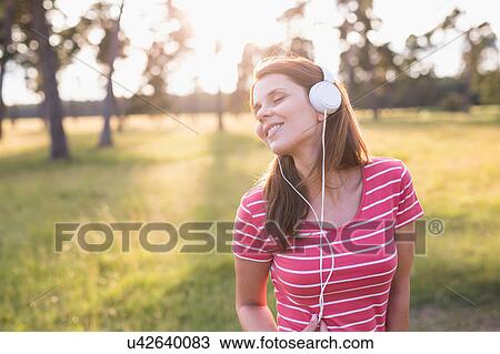 Woman dancing while listening to headphone music in field View Large Photo Image Stock Image - Woman dancing while listening to headphone music in field. Fotosearch