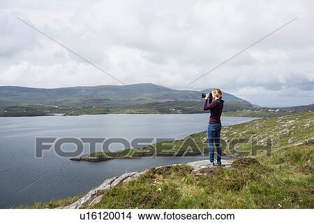 Woman photographing view, standing on north shore of East Loch Tarbet, North Harris, Outer Hebrides, Scotland View Large Photo Image Picture - Woman photographing view, standing on north shore of East Loch Tarbet, North Harris, Outer Hebrides, Scotland. Fotosearch