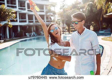 Young couple holding up water gun on poolside, Koh Samui, Thailand View Large Photo Image Stock Photography - Young couple holding up water gun on poolside, Koh Samui, Thailand. Fotosearch
