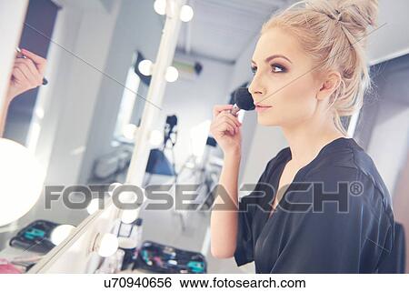 Stock Photograph - Young female model applying blusher for photo shoot. Fotosearch