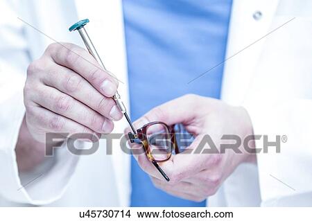 Picture - Close-up of optician repairing eyeglasses.. Fotosearch