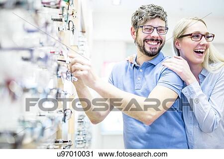 Stock Image - Couple laughing near glasses rack. Fotosearch