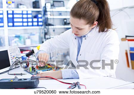 Stock Image - Female engineer working on a circuit board. Fotosearch