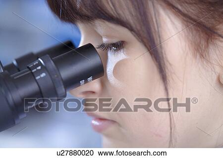 Stock Image - Female medical student using microscope. Fotosearch