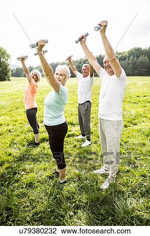Four people exercising with hand weights in field View Large Photo Image Stock Image - Four people exercising with hand weights in field. Fotosearch