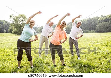 Stock Photo - Four people in field exercising. Fotosearch