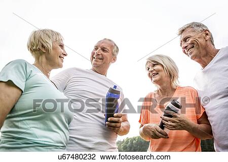 Stock Image - Four people outdoors with water bottles. Fotosearch
