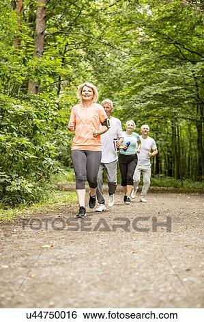 Stock Photograph - Four people running on track in woods. Fotosearch