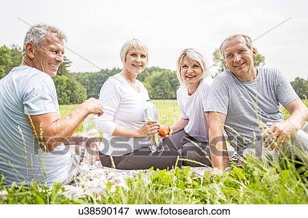 Four people sitting on grass with water View Large Photo Image Stock Photo - Four people sitting on grass with water. Fotosearch