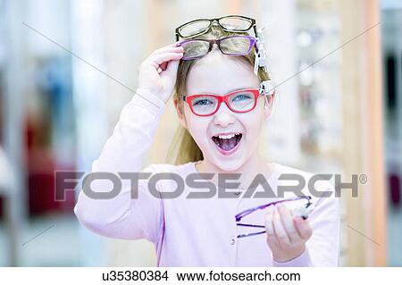 Girl trying on glasses View Large Photo Image Picture - Girl trying on glasses. Fotosearch
