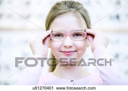 Stock Image - Girl trying on glasses. Fotosearch