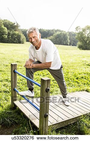 Man leaning on gate, smiling View Large Photo Image Stock Photograph - Man leaning on gate, smiling. Fotosearch
