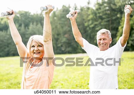 Mature couple exercising with hand weights in field View Large Photo Image Stock Image - Mature couple exercising with hand weights in field. Fotosearch