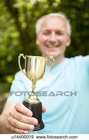 Mature man holding a trophy View Large Photo Image Stock Photo - Mature man holding a trophy. Fotosearch