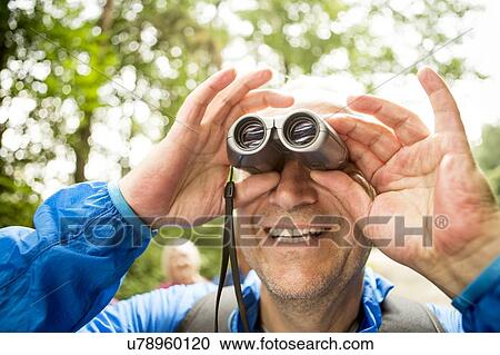 Mature man looking through binoculars View Large Photo Image Stock Image - Mature man looking through binoculars. Fotosearch