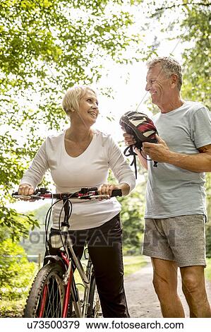 Mature woman on bike, Man holding helmet View Large Photo Image Stock Photo - Mature woman on bike, Man holding helmet. Fotosearch