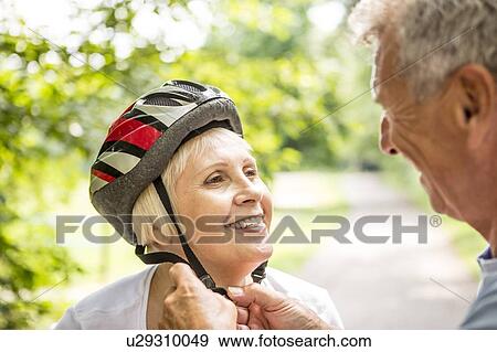 Mature woman wearing bicycle helmet, Man assisting View Large Photo Image Stock Photo - Mature woman wearing bicycle helmet, Man assisting. Fotosearch