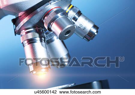 Stock Image - Microscope against blue background.. Fotosearch