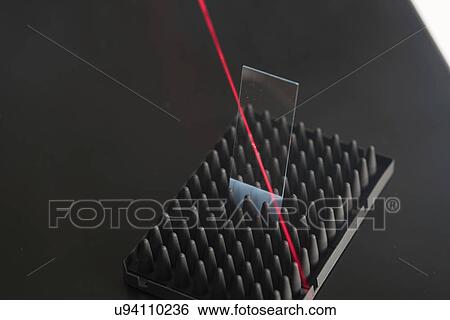 Stock Photograph - Microscope slide with red laser beam.. Fotosearch