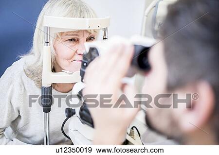 Stock Photo - Optometrist examining woman's eyes. Fotosearch