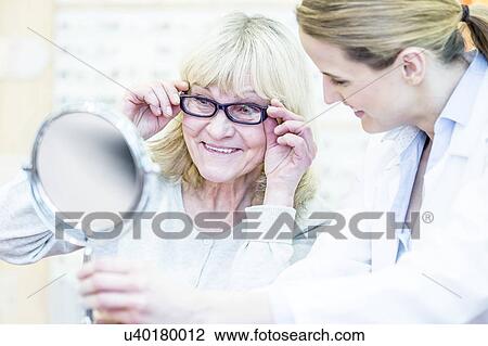Stock Image - Optometrist helping senior woman. Fotosearch