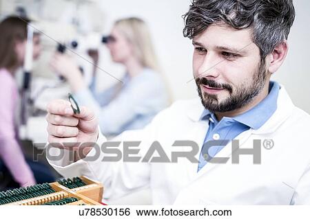 Stock Photograph - Optometrist holding lens. Fotosearch