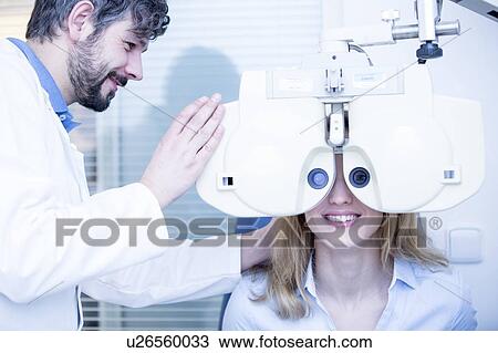 Stock Image - Optometrist performing eye test. Fotosearch