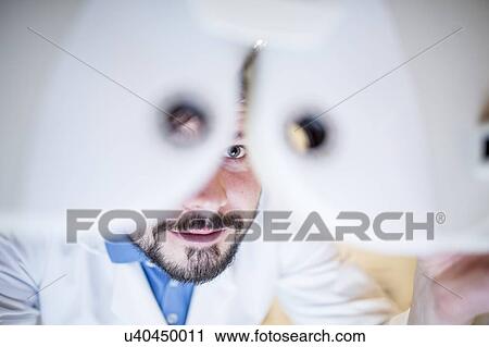 Stock Image - Optometrist performing eye test. Fotosearch