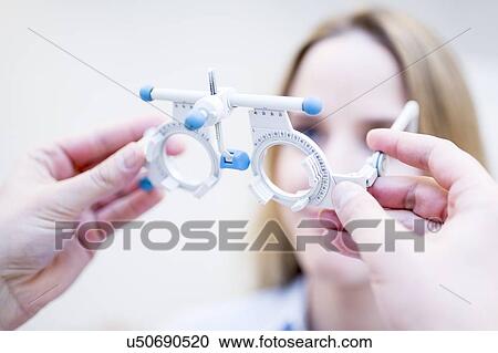 Stock Image - Optometrist performing eye test. Fotosearch
