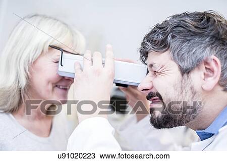 Stock Image - Optometrist performing eye test. Fotosearch