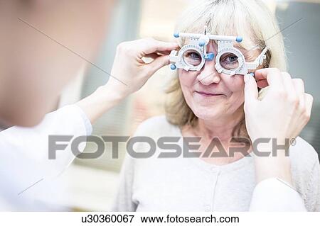 Optometrist performing eye test View Large Photo Image Stock Photo - Optometrist performing eye test. Fotosearch