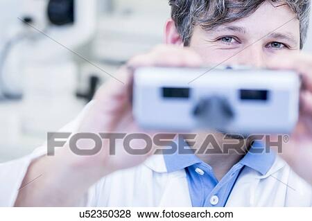 Stock Photo - Optometrist performing eye test. Fotosearch
