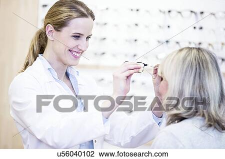 Optometrist trying glasses on woman View Large Photo Image Stock Image - Optometrist trying glasses on woman. Fotosearch