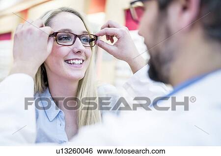 Optometrist trying glasses on woman View Large Photo Image Stock Photograph - Optometrist trying glasses on woman. Fotosearch