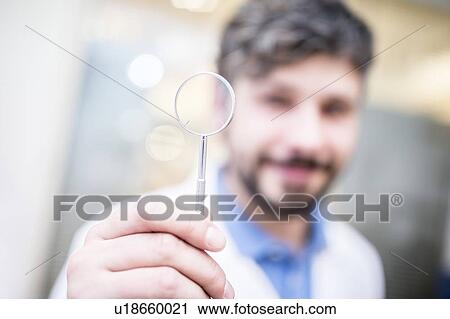 Stock Image - Optometrist with magnifying glass. Fotosearch