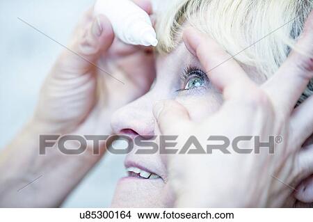 Picture - Person applying eye drops. Fotosearch