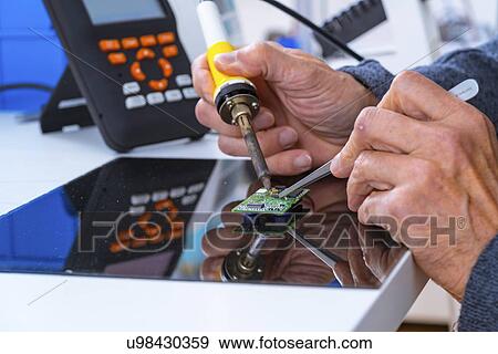 Stock Photo - Person soldering an electronic component.. Fotosearch