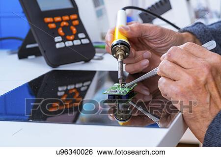 Stock Photograph - Person soldering an electronic component.. Fotosearch