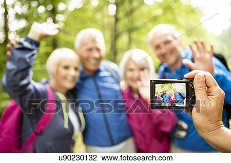 Stock Image - Person taking photo of four hikers with digital camera. Fotosearch