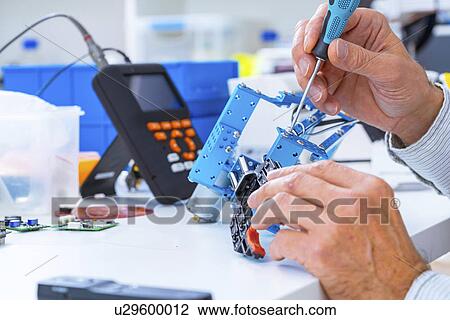 Stock Image - Person working with robotic parts.. Fotosearch