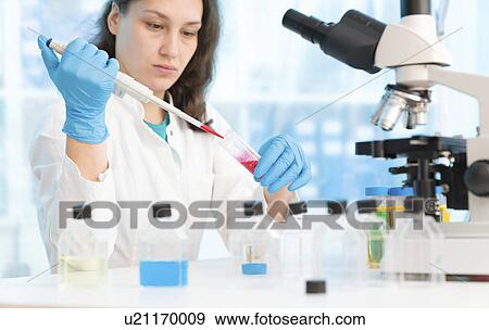 Stock Photo - Scientist holding test tube and using pipette. Fotosearch