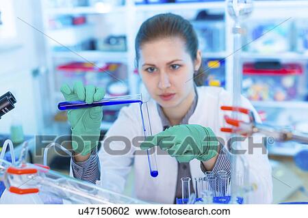 Stock Image - Scientist pouring liquid into test tube. Fotosearch
