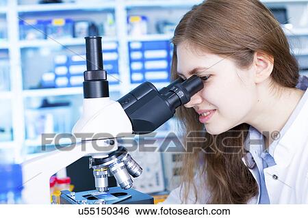 Stock Photograph - Scientist using microscope. Fotosearch
